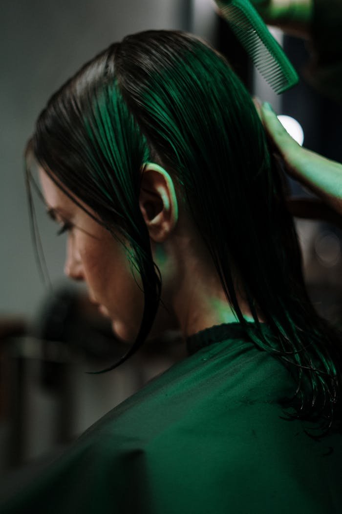 Side view of a woman getting a haircut with wet hair in a salon setting.